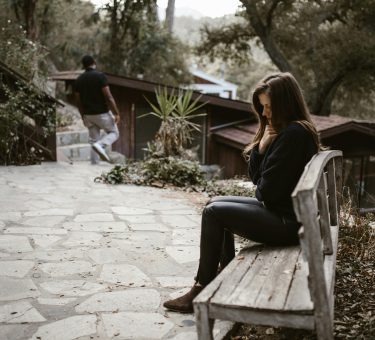 Person checking phone anxiously — how to stop being clingy in a relationship